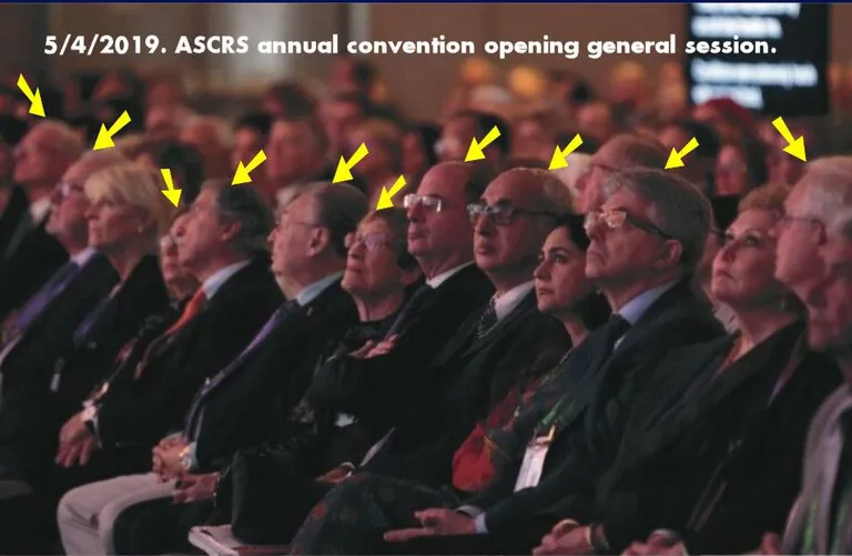 Audience at the 2019 ASCRS annual convention, with yellow arrows pointing to people wearing glasses.